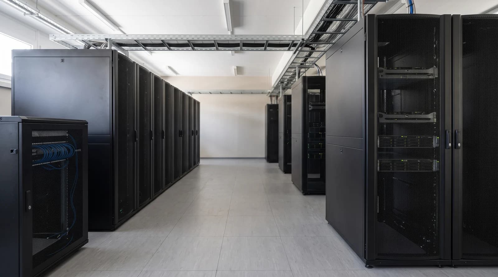 An aisle between equipment cabinets with overhead cable trays in a data center