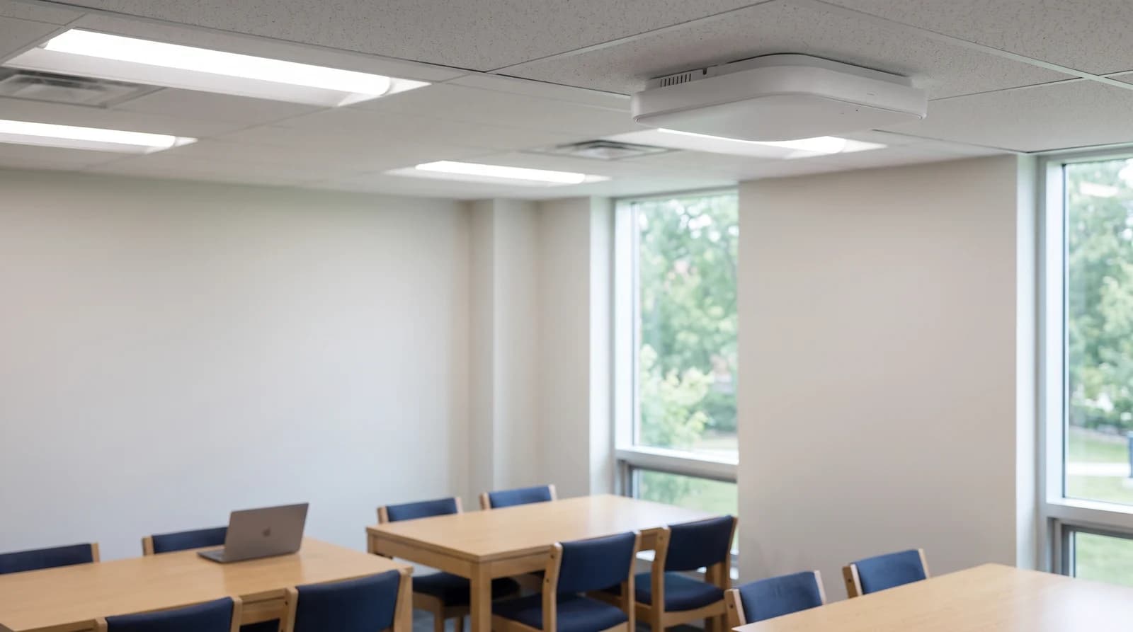 A ceiling-mounted Wi-Fi access point above tables in a shared university study space